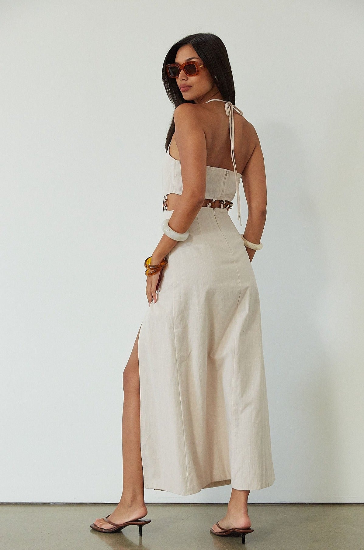 Woven maxi dress. Adjustable halter tie neckline. Back hook and eye and zipper closures. Ring waist details. Front slit. Fully lined. tan maxi dress. beige maxi dress. summer vacation dress. 