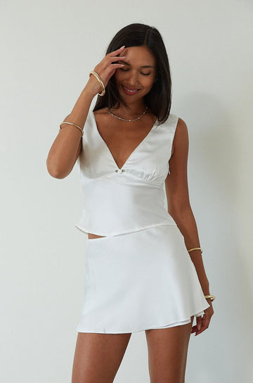 Satin sleeveless crop top. Fixed straps. Front flower detail. Side zipper closure. Back tie closure. Partially lined. white satin tank top. satin tank top. summer top