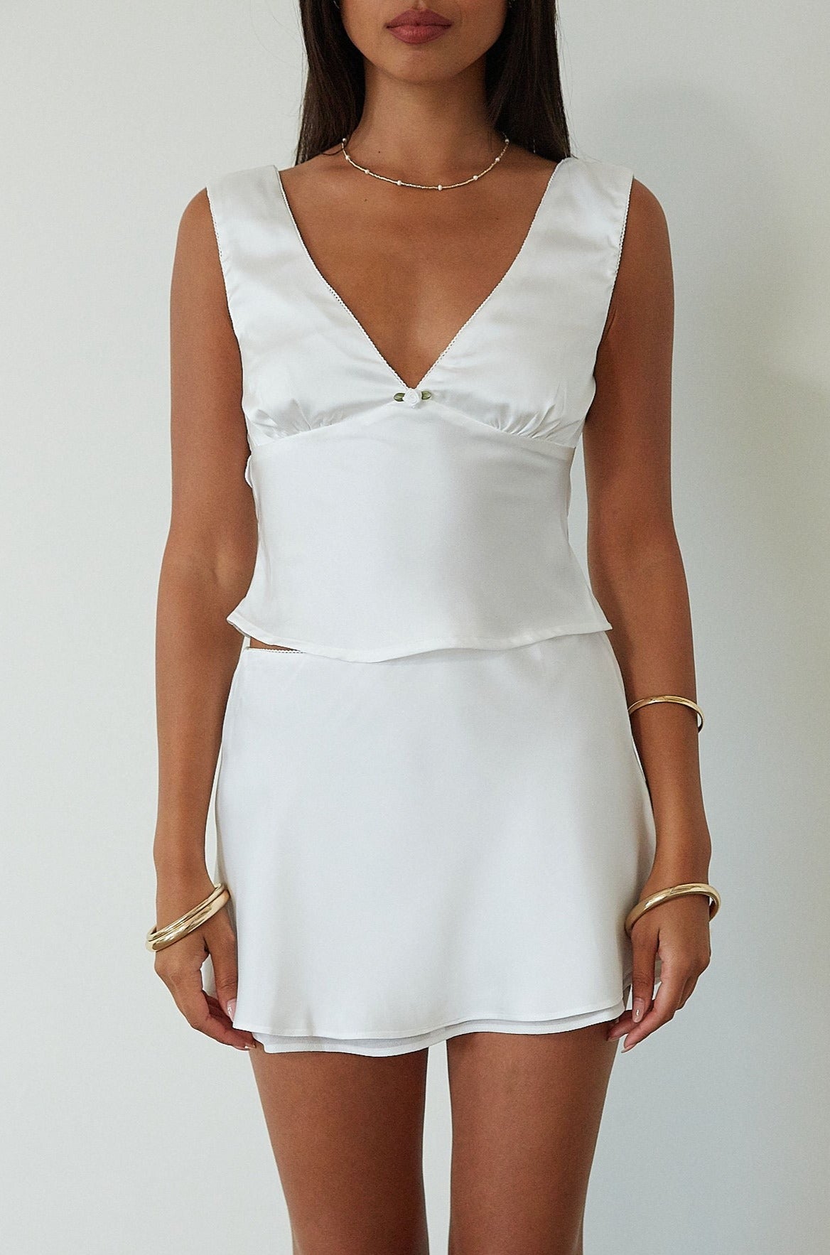 Satin sleeveless crop top. Fixed straps. Front flower detail. Side zipper closure. Back tie closure. Partially lined. white satin tank top. satin tank top. summer top