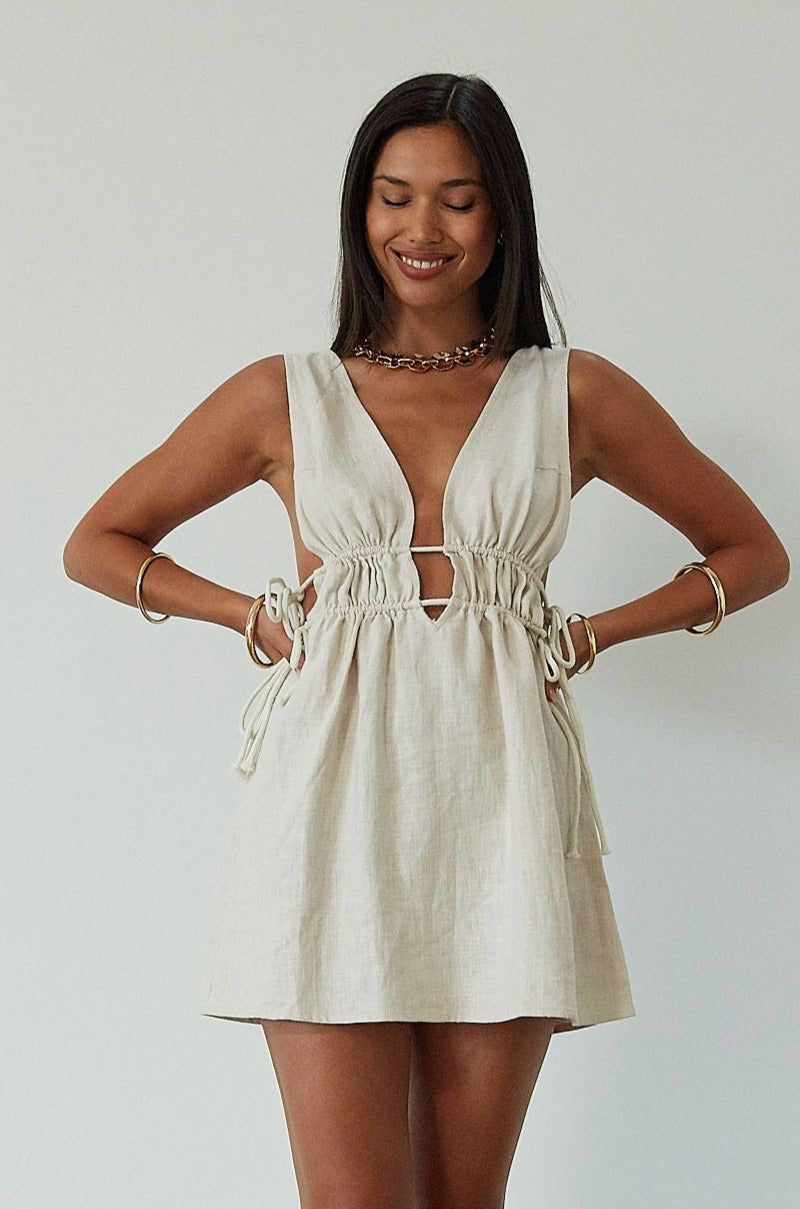 Woven sleeveless dress. Fixed straps. Adjustable drawstring waist. Unlined. tan mini dress. cream mini dress. summer dress. dinner dress. evening dress. vacation dress. vacation outfit