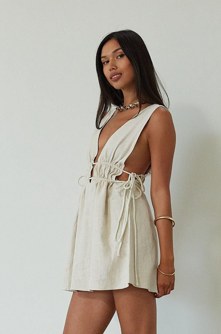 Woven sleeveless dress. Fixed straps. Adjustable drawstring waist. Unlined. tan mini dress. cream mini dress. summer dress. dinner dress. evening dress. vacation dress. vacation outfit