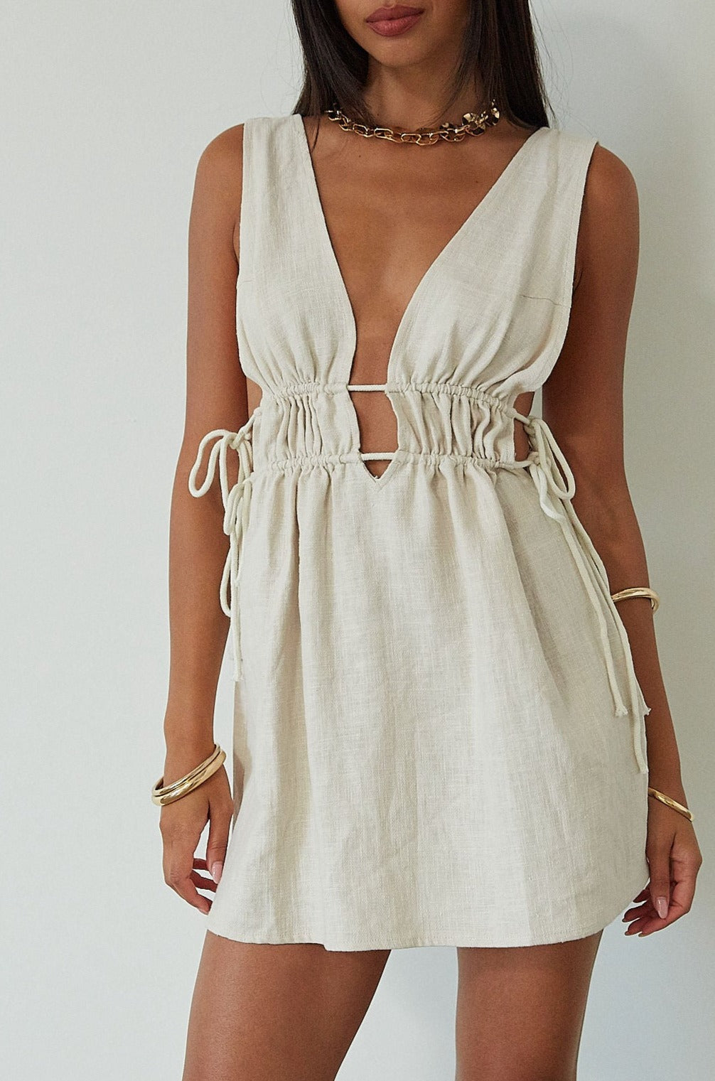 Woven sleeveless dress. Fixed straps. Adjustable drawstring waist. Unlined. tan mini dress. cream mini dress. summer dress. dinner dress. evening dress. vacation dress. vacation outfit