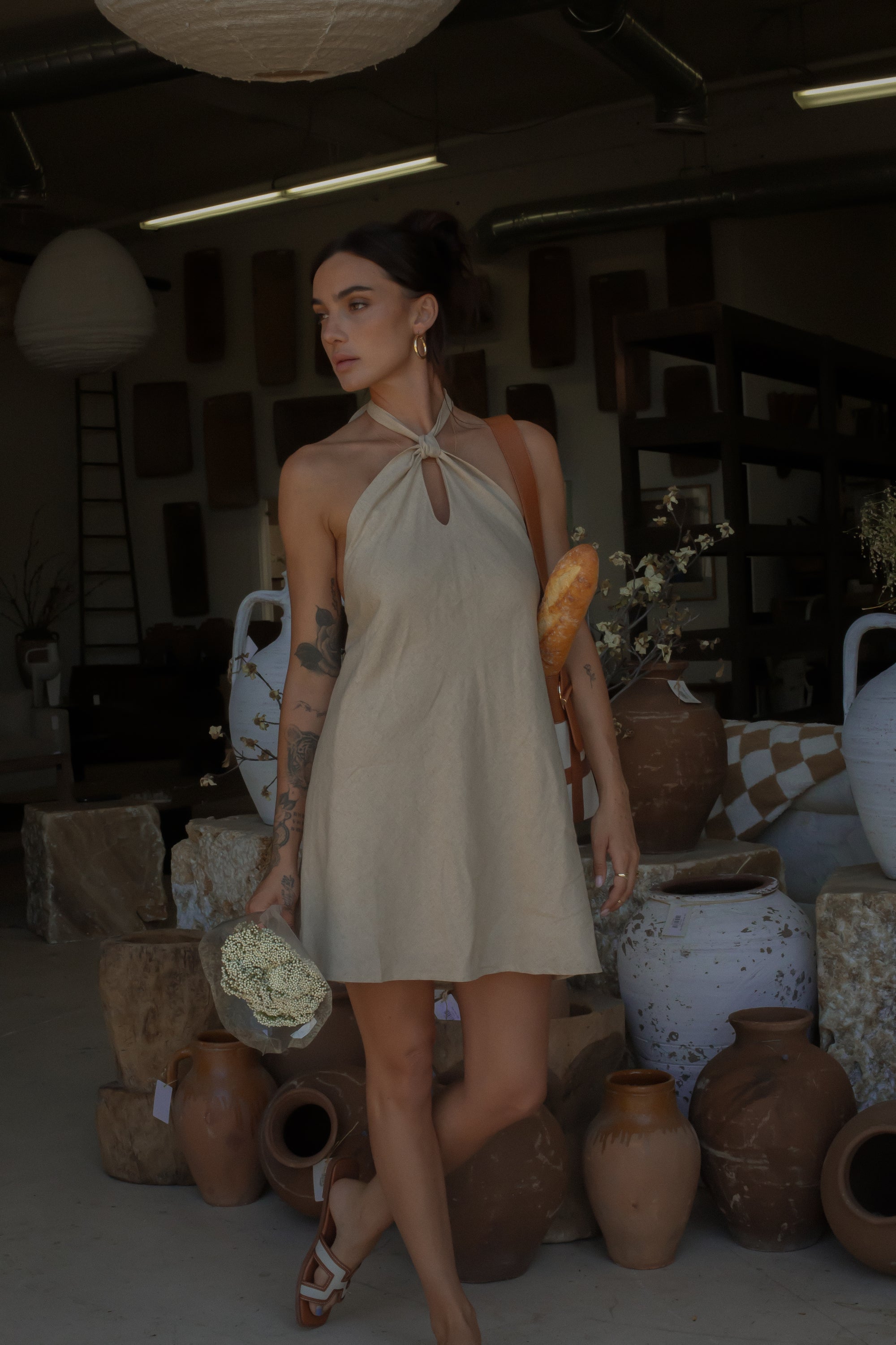Woven dress. Adjustable halter neckline with tie closure. Back hook and eye and zipper closures. Fully lined. European summer. European summer dress. European summer aesthetic. Tuscany outfit inso. Tuscany aesthetic. Summer dress. oat mini dress. beige mini dress. tan mini dress. mini halter neck dress. summer outfit. everyday dress. vacation dress. outfit to wear to tuscany. nice dinner dress. dinner dress. day dress. 