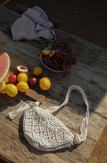 Woven macrame crossbody bag. Fixed strap. Fringe trim. Front zipper closure. Fully lined.