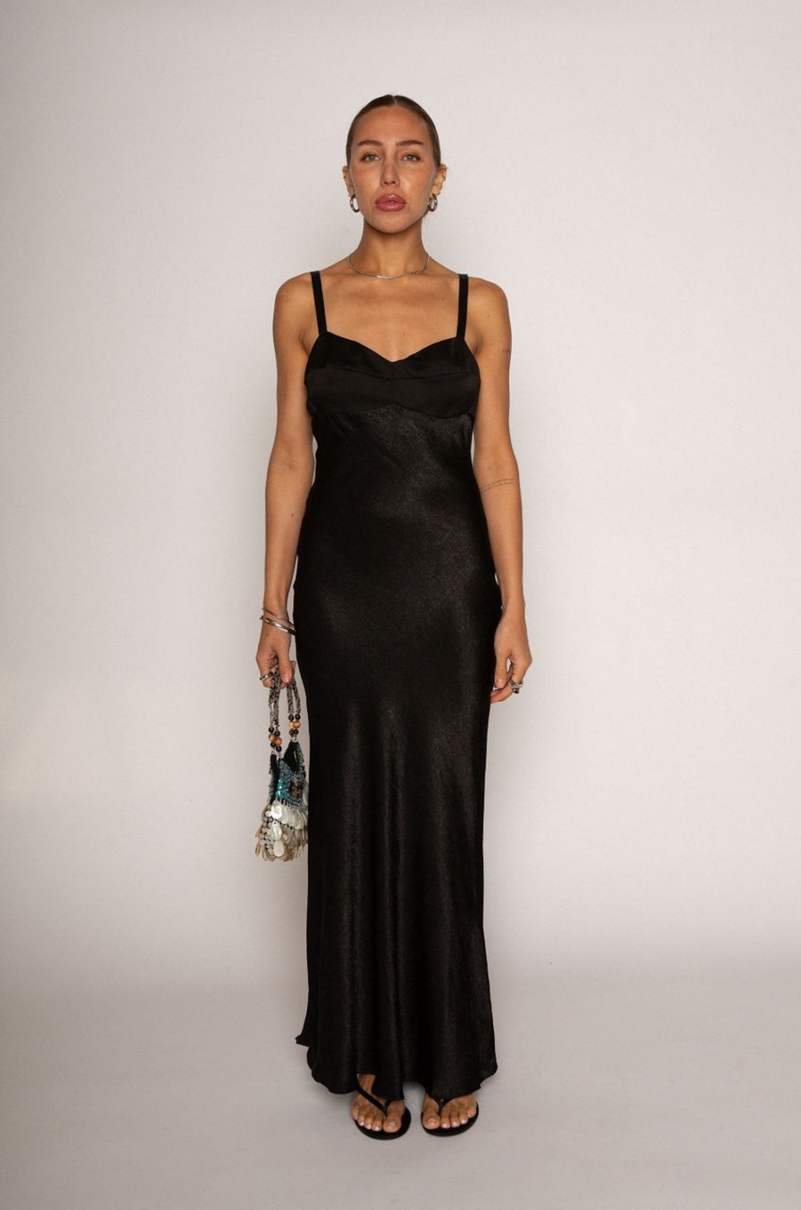 Textured black satin maxi dress. Adjustable elastic straps. Back hook and eye and zipper closures. Partially lined. black wedding guest dress