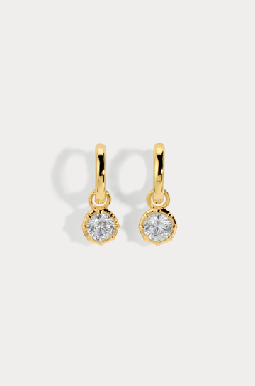 A modern bezel set charm hoop that pairs clean design with luminous sparkle
Available in 14kt gold plated brass or Rhodium plated brass
Stones are white cz and measure 5.0mm each
Huggie measures 8mm inner diameter.
Snap Hinge Closure
Sold as a pair
gold cz hoop earring