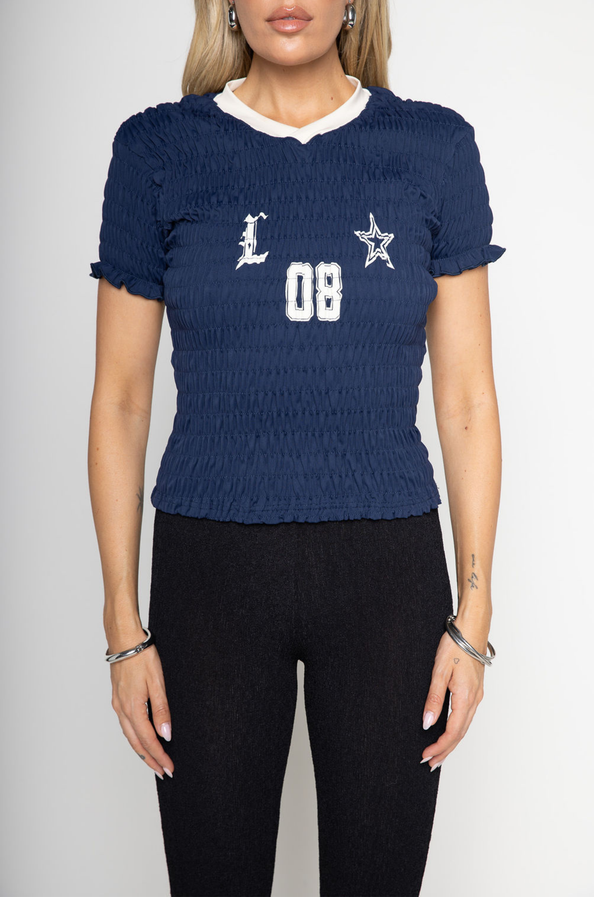 Graphic printed elastic smocked crop top. V-neckline. Short sleeves. Contrast detailing. navy tee. lioness scrunched graphic tee