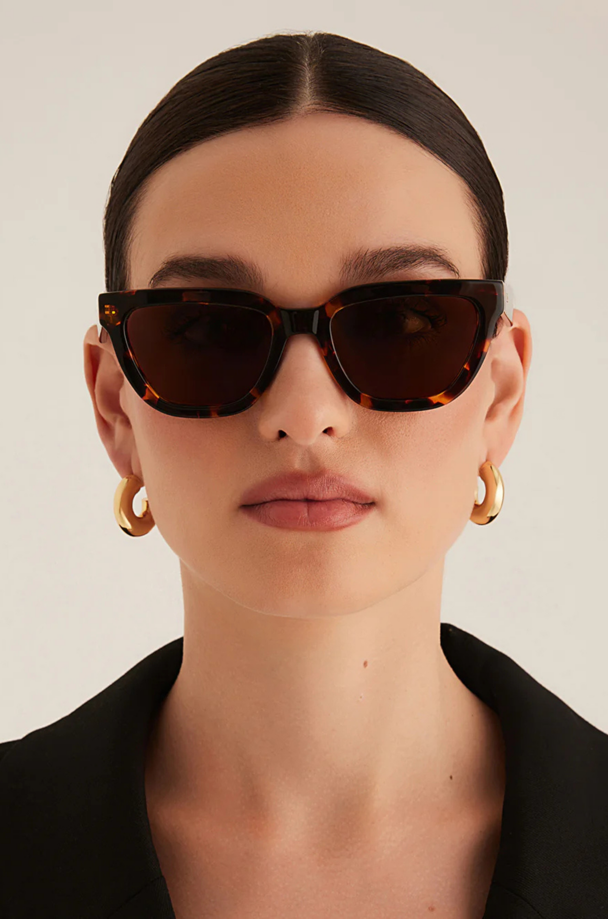 Person wearing tortoiseshell sunglasses with a neutral background
Tort cat eye sunglasses