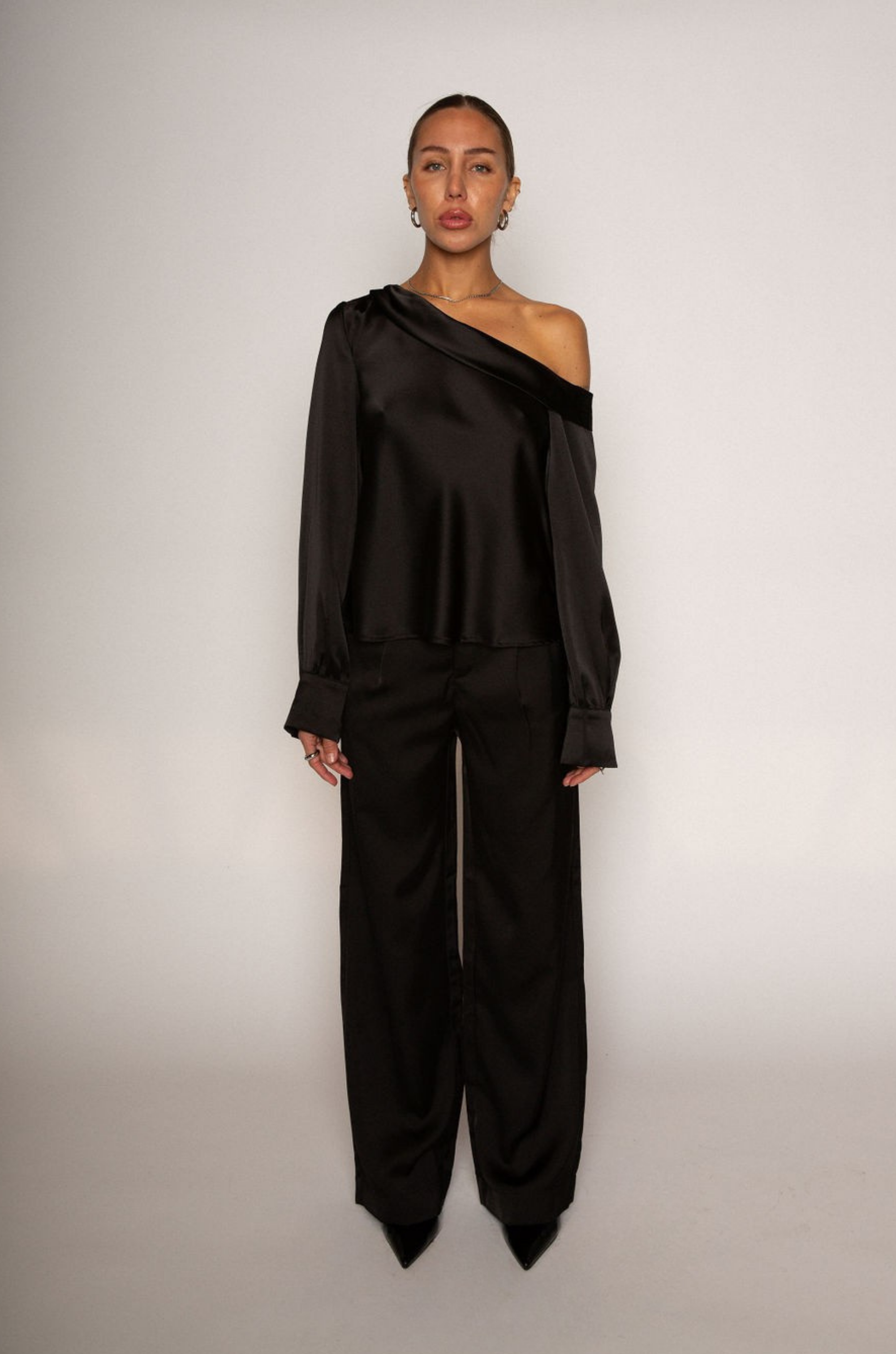 black Satin top. Folded off the shoulder neckline. Long sleeves with button closures. Unlined. black satin off the shoulder top.