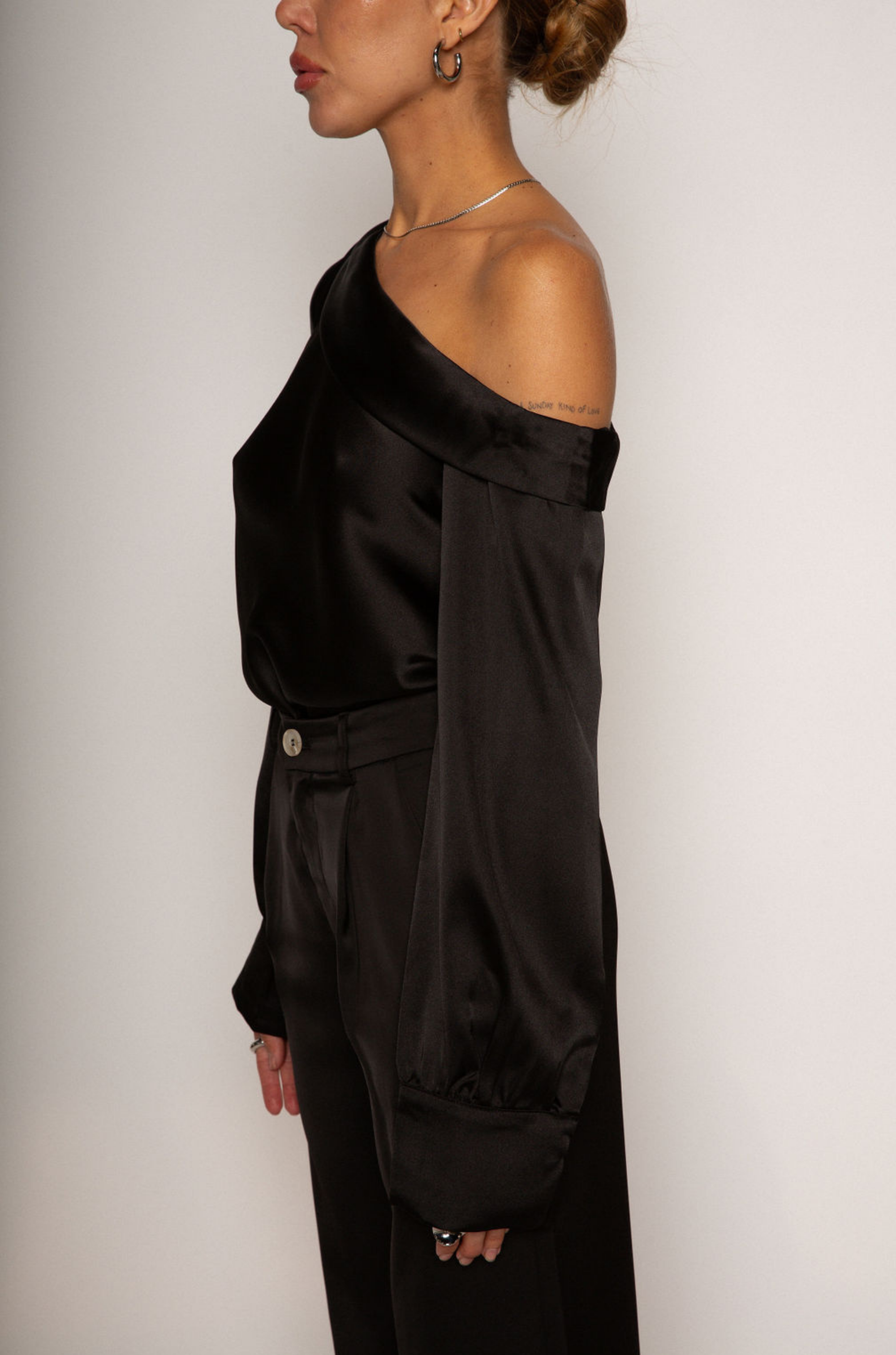 black Satin top. Folded off the shoulder neckline. Long sleeves with button closures. Unlined. black satin off the shoulder top.