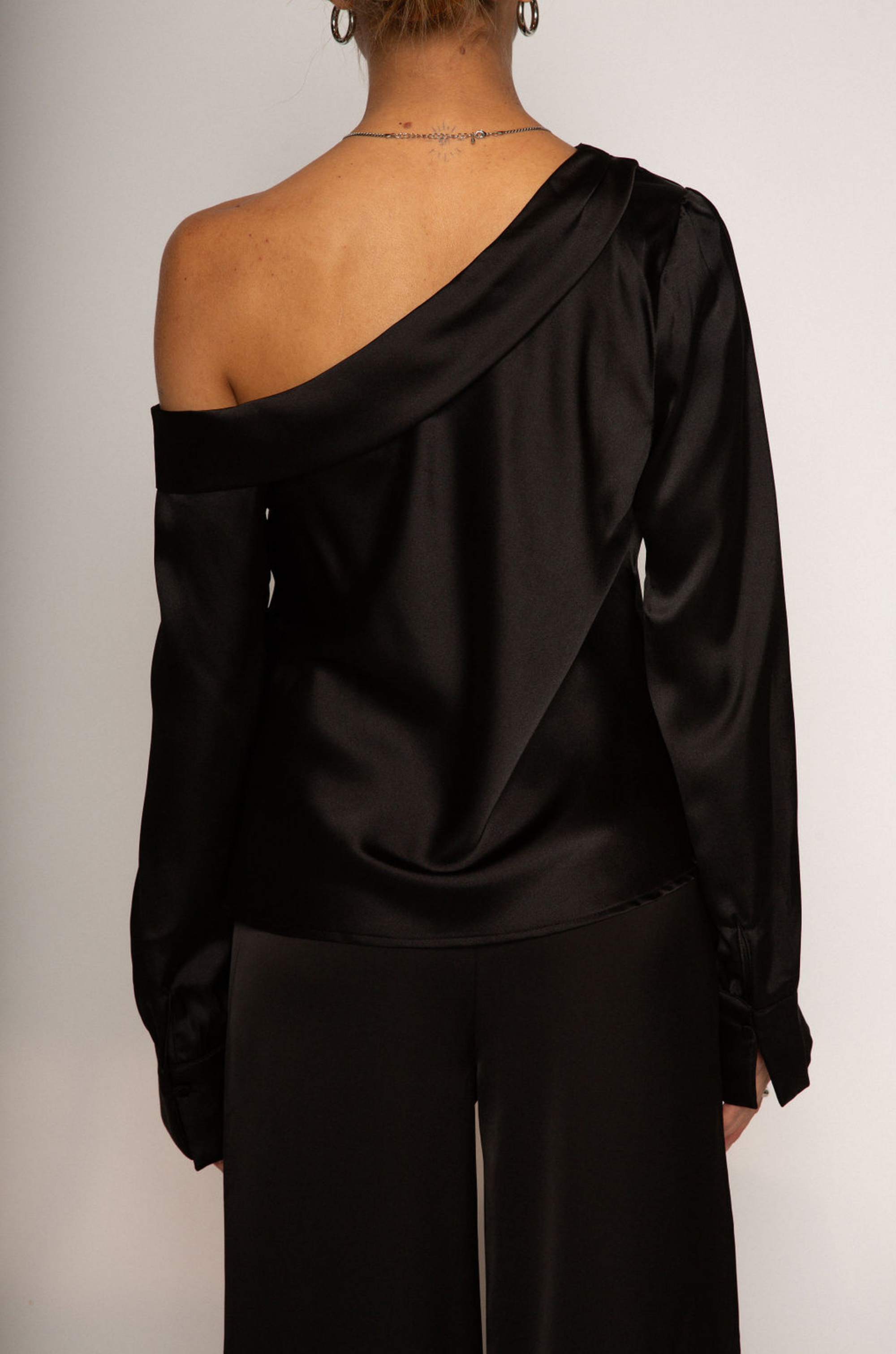 black Satin top. Folded off the shoulder neckline. Long sleeves with button closures. Unlined. black satin off the shoulder top.