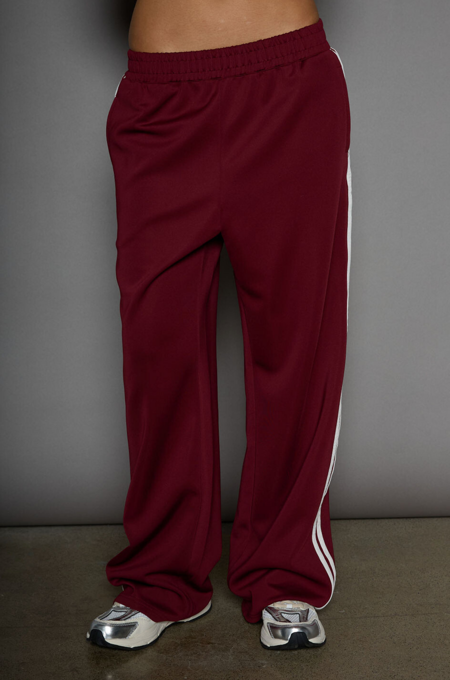 Woven burgundy track pants. Elastic waistband. Side pockets. Side stripes. Unlined. street fashion. trendy track pants