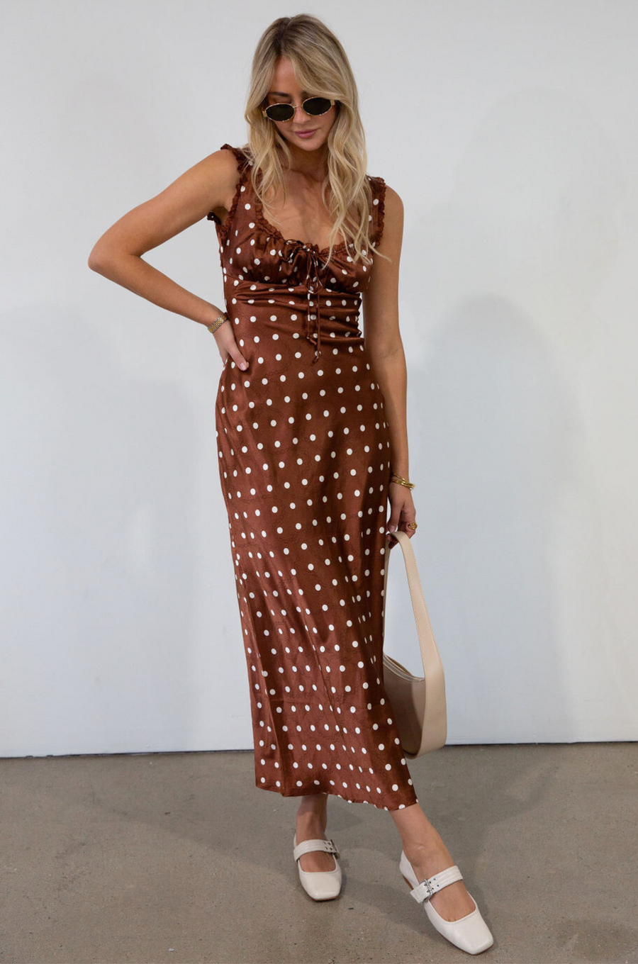 brown and white Polka dot printed satin maxi dress. Fixed straps. Lace trimmed neckline. Front drawstring closure. Side hook and eye and zipper closures. Back tie closure. Elastic back. Fully lined. fall dress. fall wedding guest dress. fall outfit