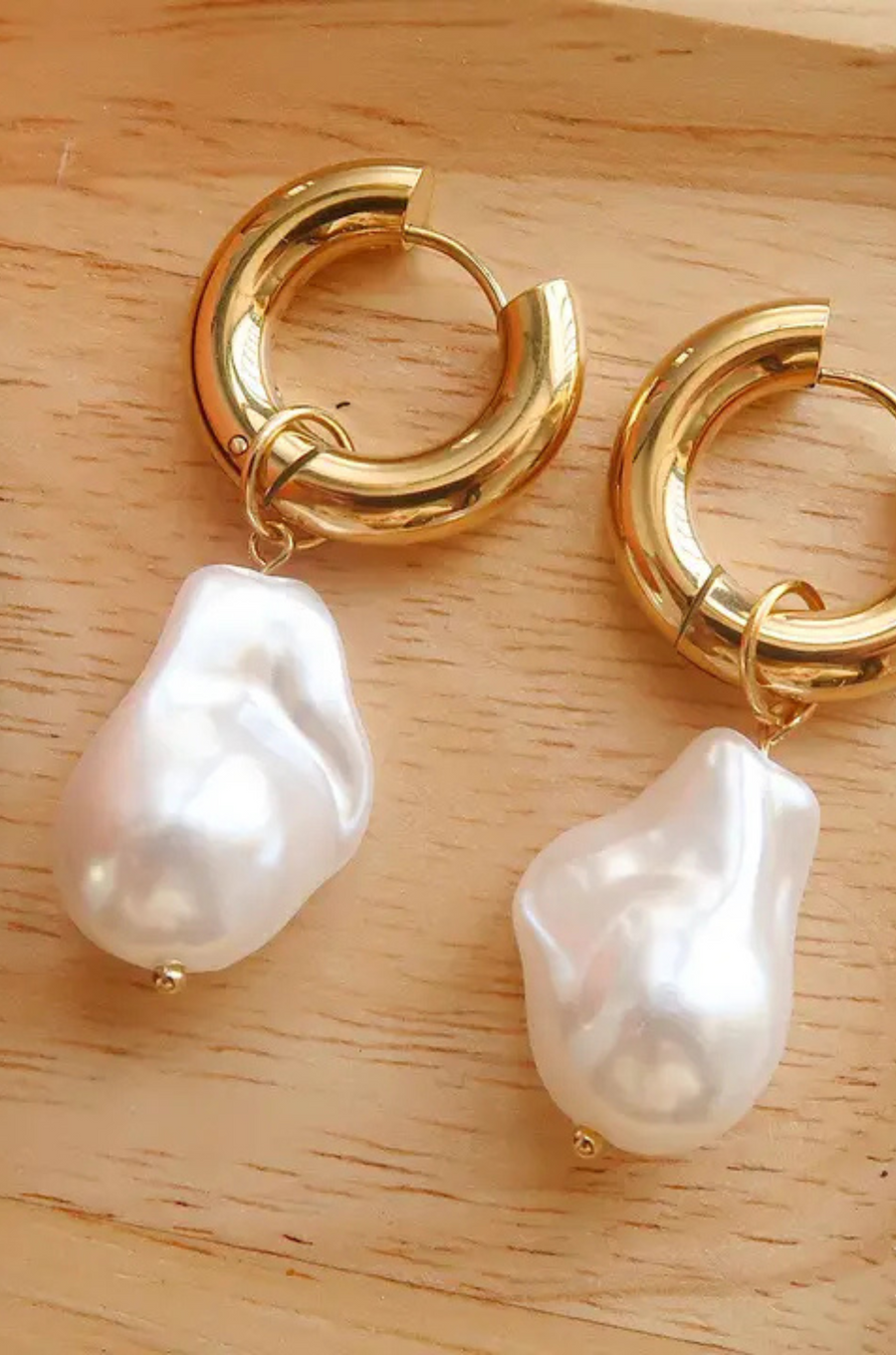 Small thick hoop earrings with pearl drop detail. Hinge closure.