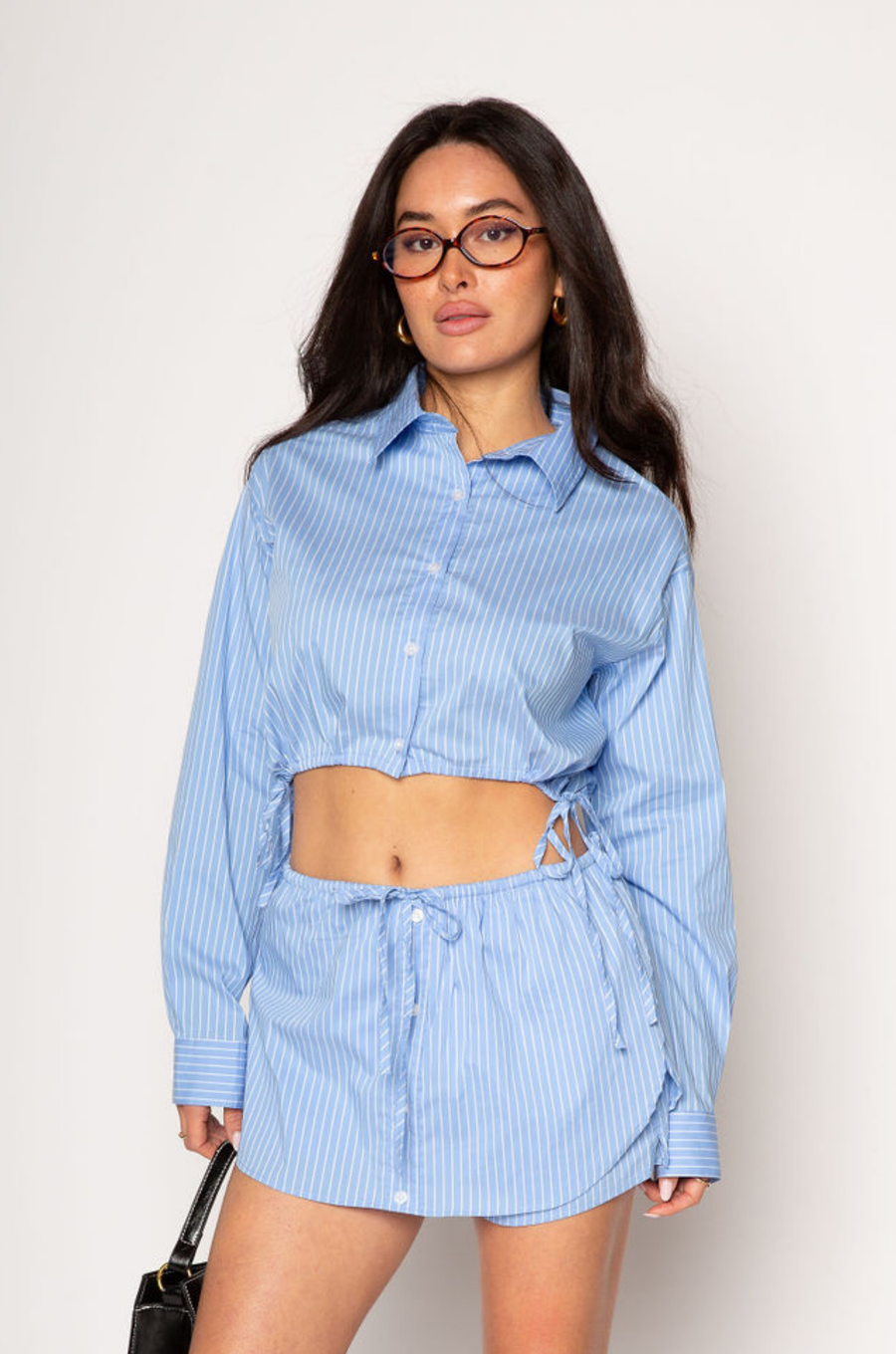 Striped woven cropped shirt. Collar neckline. Long sleeves with button closures. Front button down closures. Drawstring side ties. Unlined. blue stripe crop top. studious oufit