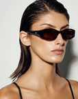 Vintage-inspired sunglasses. Featuring a sleek horizontally elongated oval shape with softly rounded lenses, this statement silhouette is set within a thick dark frame that slightly widens at the outer edges for a modern sporty finish.

Featuring:

elongated oval frame silhouette
acetate frame
softly rounded lens shape
thick dark frame design with widened outer edges
retro-inspired sporty aesthetic
smooth curved detailing
polarisation degree | A degree
UV protection | Cat 3