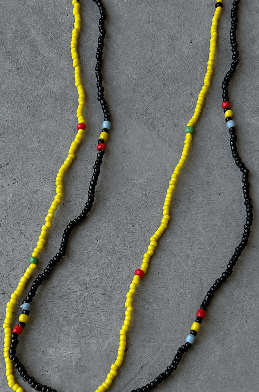Two separate elastic multicolor beaded belly chains. yellow and black belly chain
