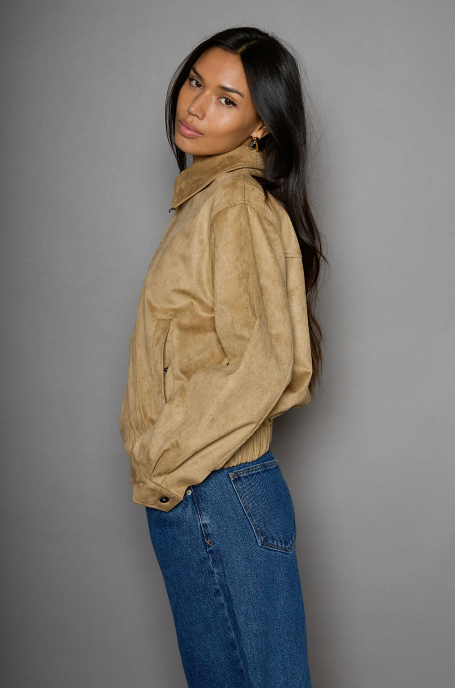 Vegan suede bomber jacket. Collar neckline. Front zipper closure. Elastic hems. Front pockets with snap button closures. Fully lined. tan suede bomber