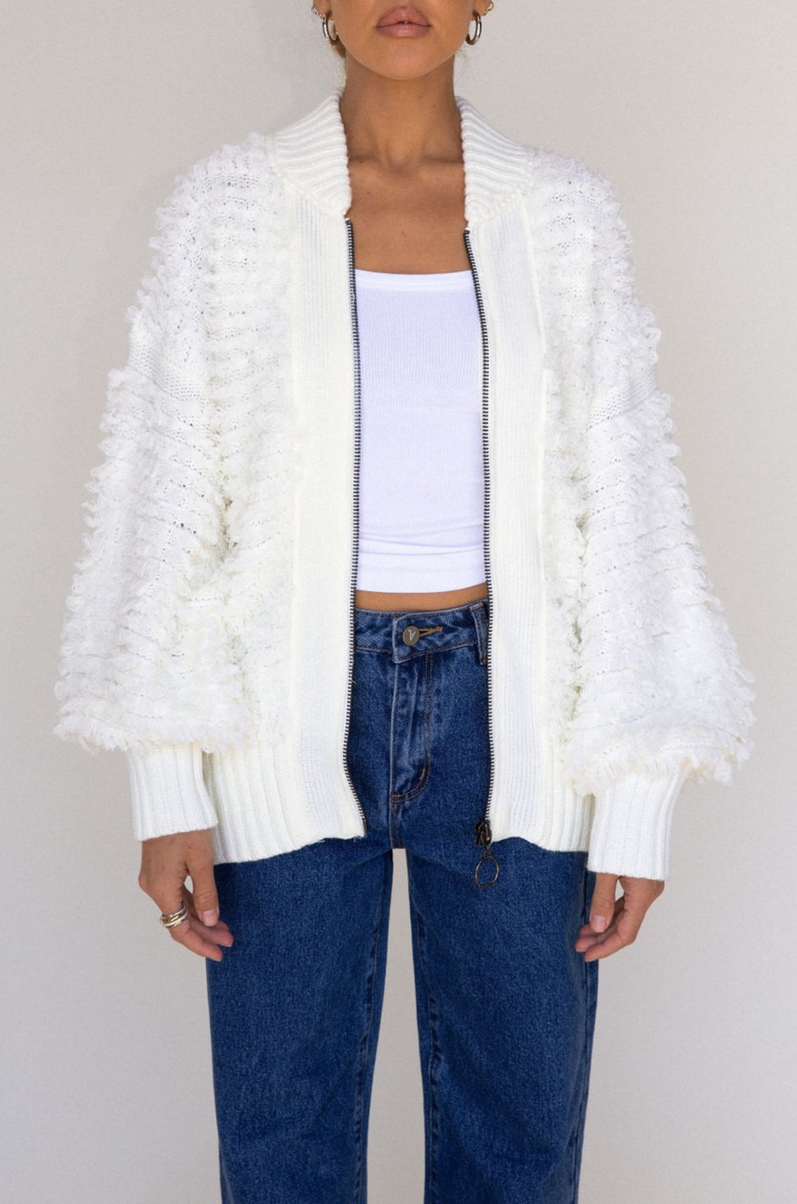 white Fringe crochet knit sweater
Front zipper closure
Long sleeves
Side pockets
Banded hems
Unlined