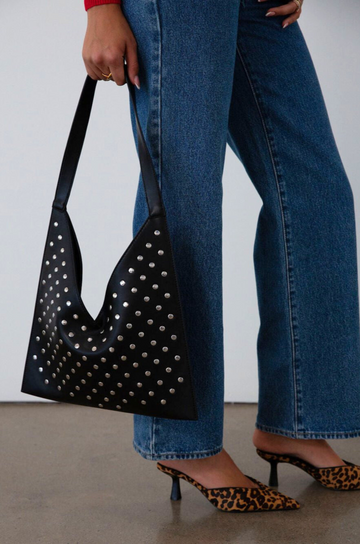 Studded vegan leather bag. Fixed top strap. Top snap button closure. Fully lined. Inner pockets and zipper pocket.
