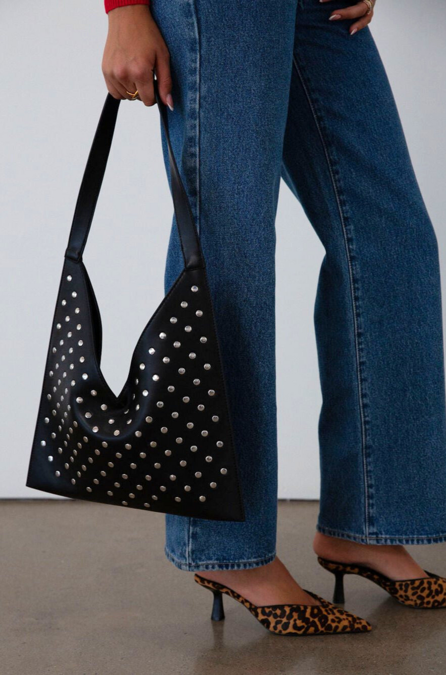 Studded vegan leather bag. Fixed top strap. Top snap button closure. Fully lined. Inner pockets and zipper pocket.