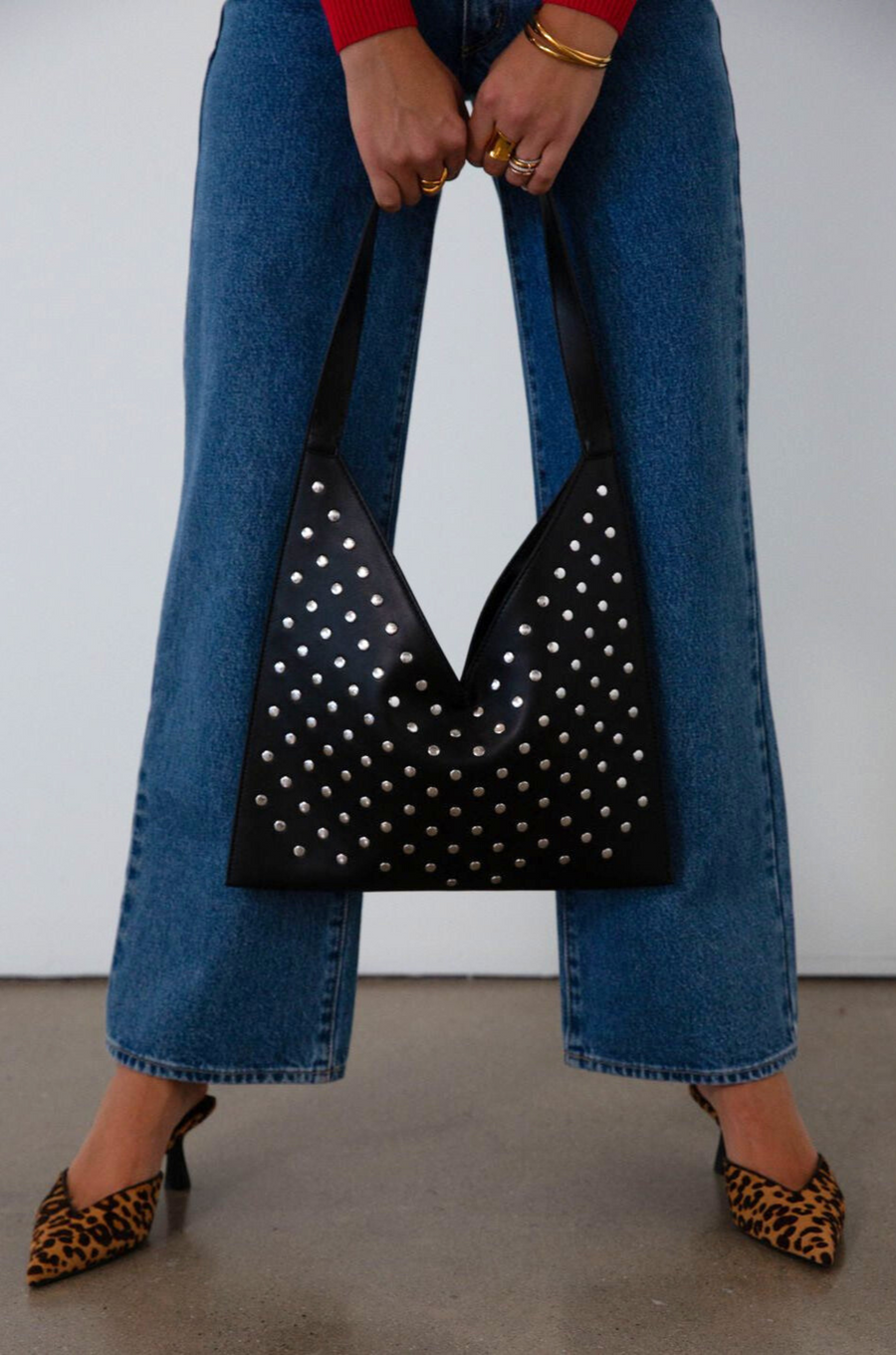 Studded vegan leather bag. Fixed top strap. Top snap button closure. Fully lined. Inner pockets and zipper pocket.