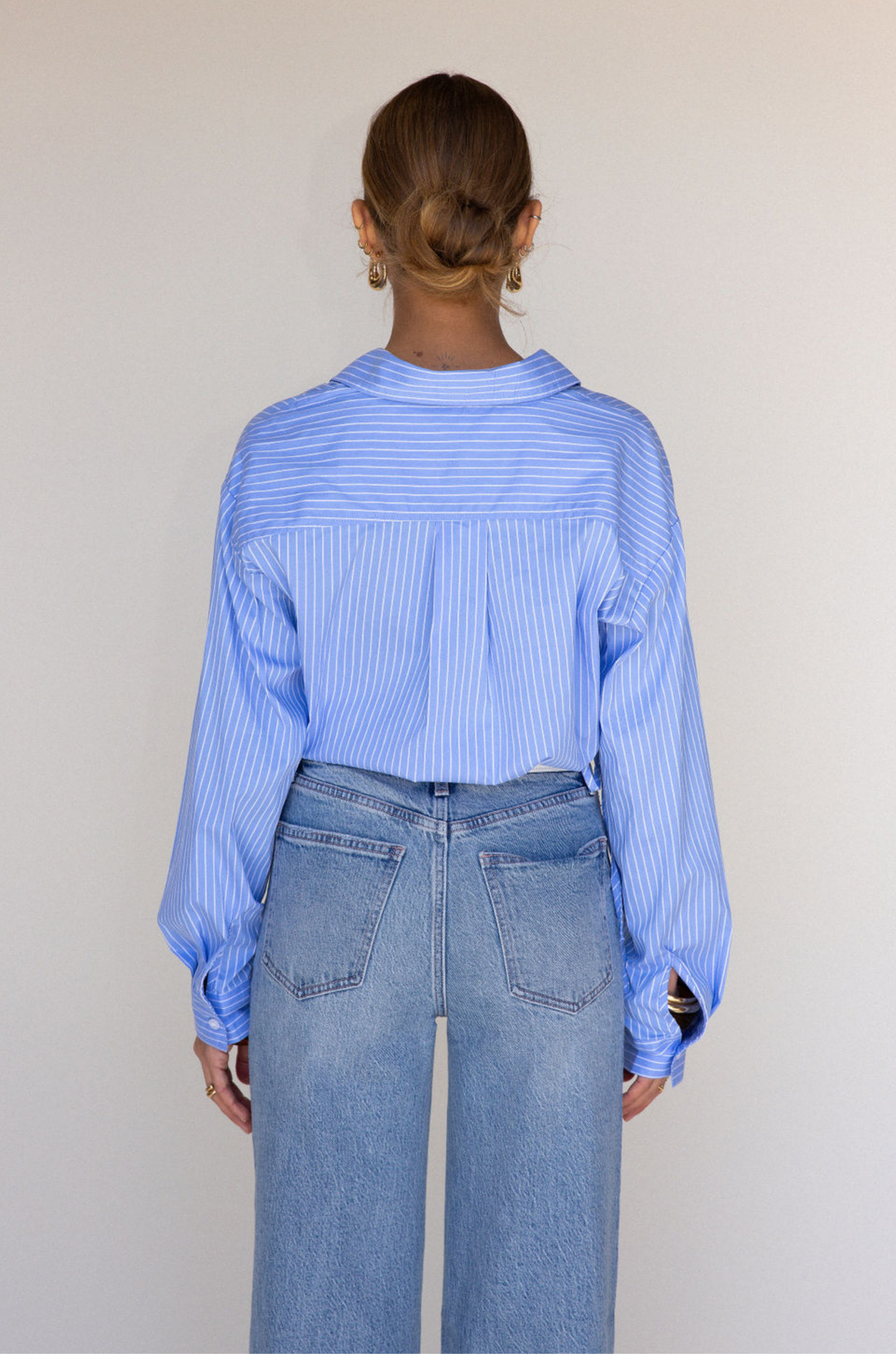 Striped woven cropped shirt. Collar neckline. Long sleeves with button closures. Front button down closures. Drawstring side ties. Unlined. blue stripe crop top. studious oufit