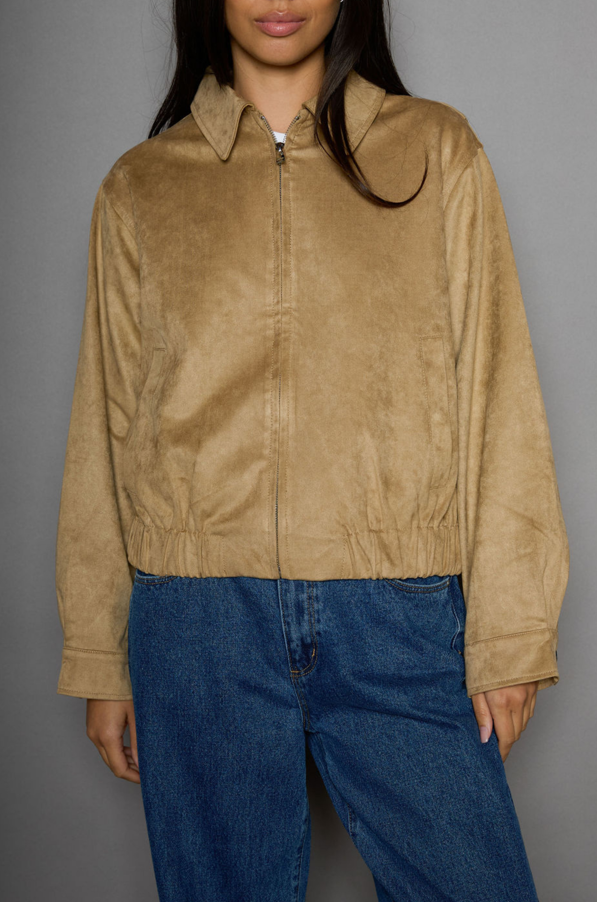 Vegan suede bomber jacket. Collar neckline. Front zipper closure. Elastic hems. Front pockets with snap button closures. Fully lined. tan suede bomber