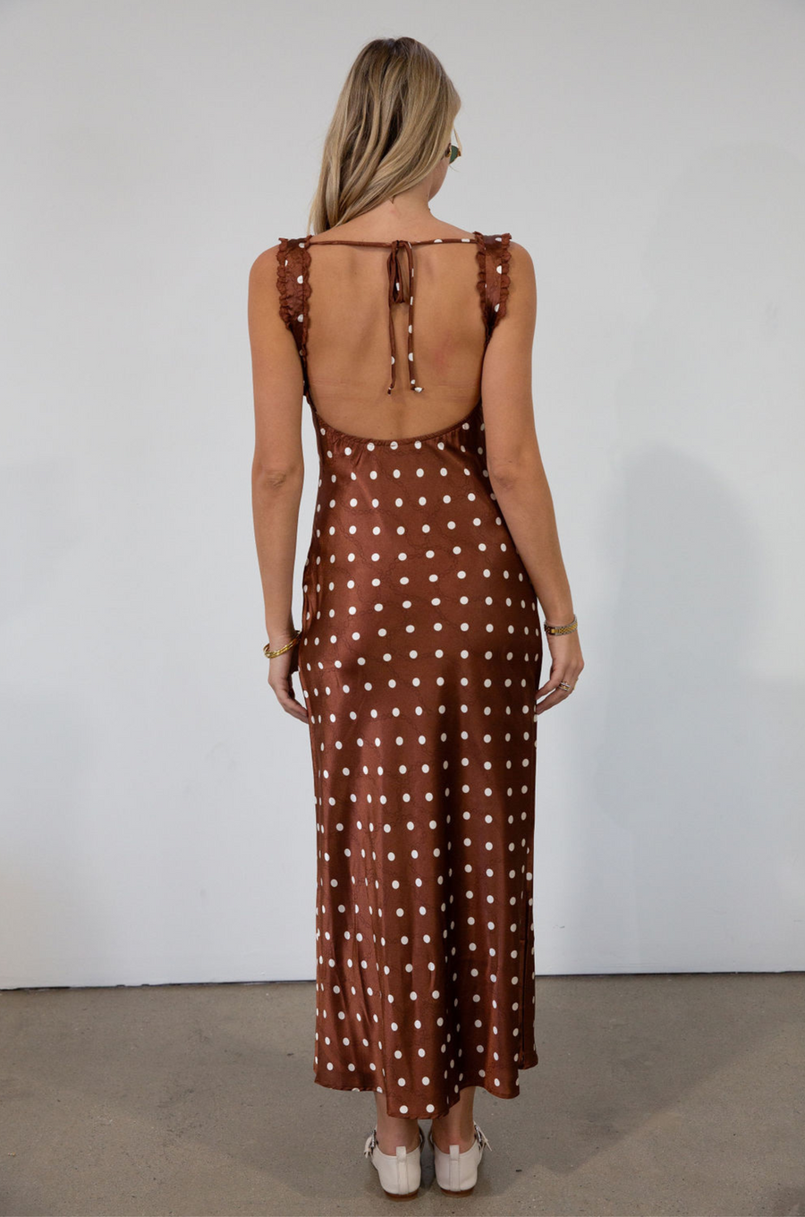 brown and white Polka dot printed satin maxi dress. Fixed straps. Lace trimmed neckline. Front drawstring closure. Side hook and eye and zipper closures. Back tie closure. Elastic back. Fully lined. fall dress. fall wedding guest dress. fall outfit