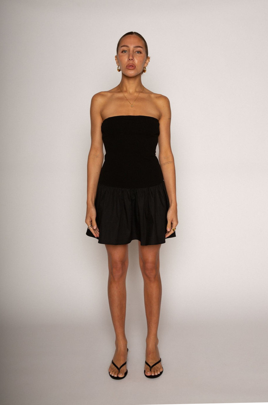 Strapless dress. Knit bodice. Woven skirt. Elastic neckline. Inner rubber grip lining. Side hook and eye and zipper closures. Unlined. Black mini dress. fall dress. holiday dress. friendsgiving dress. thanksgiving dress. summer dress. little black dress