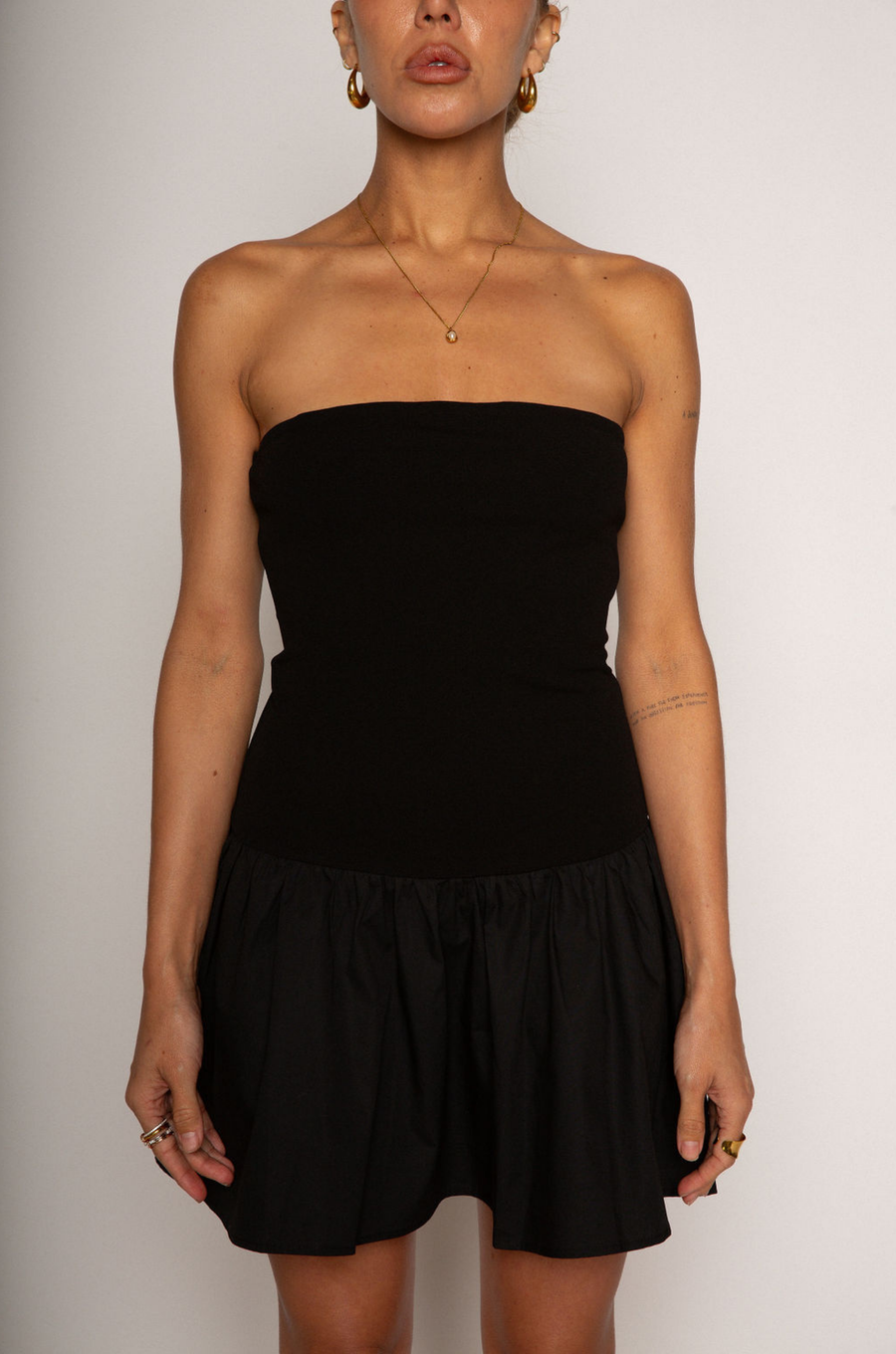 Strapless dress. Knit bodice. Woven skirt. Elastic neckline. Inner rubber grip lining. Side hook and eye and zipper closures. Unlined. Black mini dress. fall dress. holiday dress. friendsgiving dress. thanksgiving dress. summer dress. little black dress