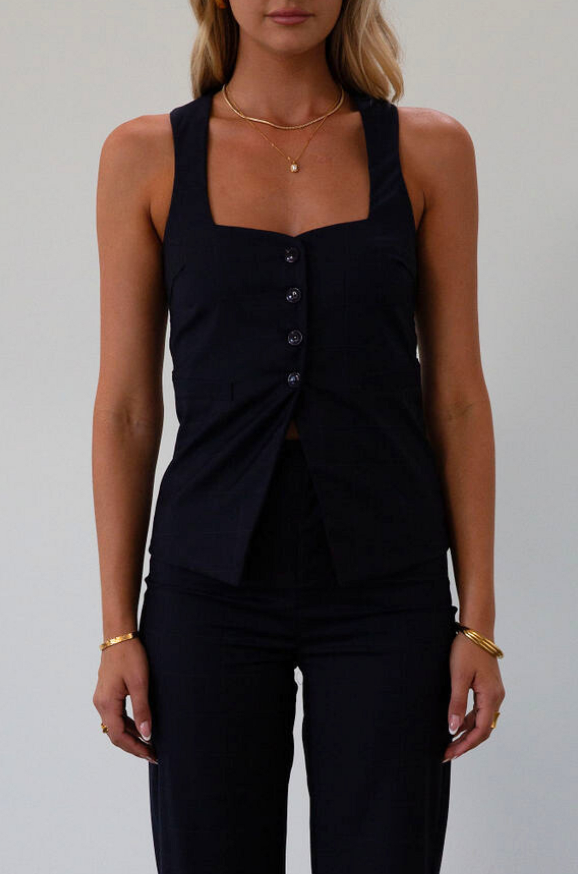 Plaid woven sleeveless top. Front button down closure. Faux front pockets. Adjustable back tie closure. Fully lined. navy blue blouse. work outfit. business casual outfit. 