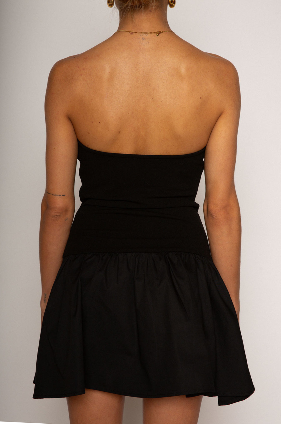 Strapless dress. Knit bodice. Woven skirt. Elastic neckline. Inner rubber grip lining. Side hook and eye and zipper closures. Unlined. Black mini dress. fall dress. holiday dress. friendsgiving dress. thanksgiving dress. summer dress. little black dress
