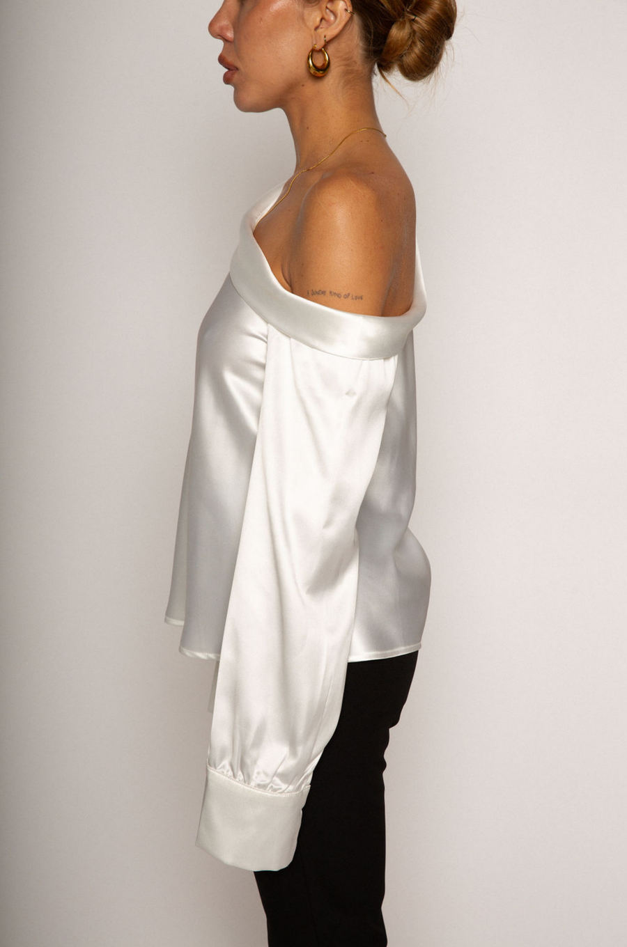 white Satin top. Folded off the shoulder neckline. Long sleeves with button closures. Unlined. white satin one shoulder top. 