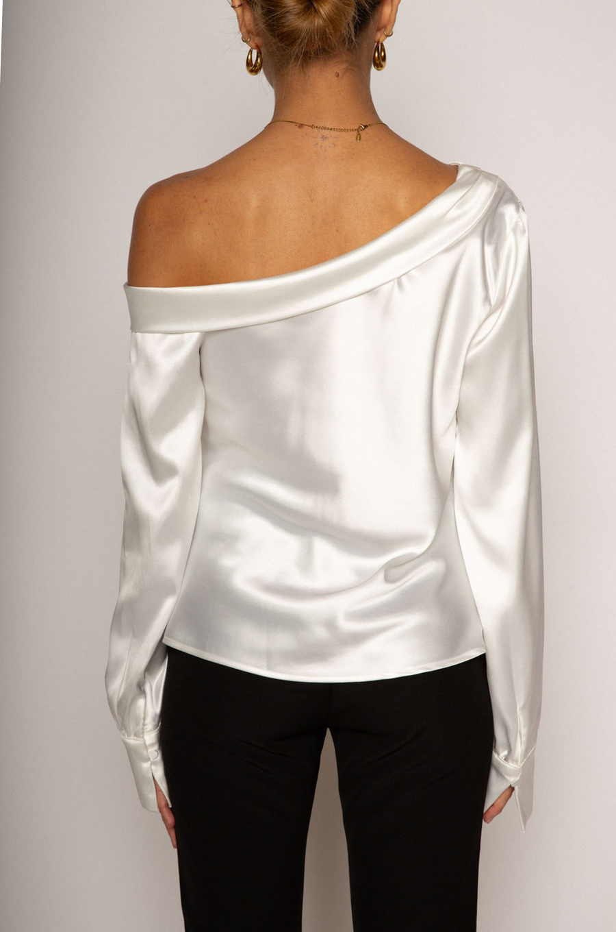 white Satin top. Folded off the shoulder neckline. Long sleeves with button closures. Unlined. white satin one shoulder top. 