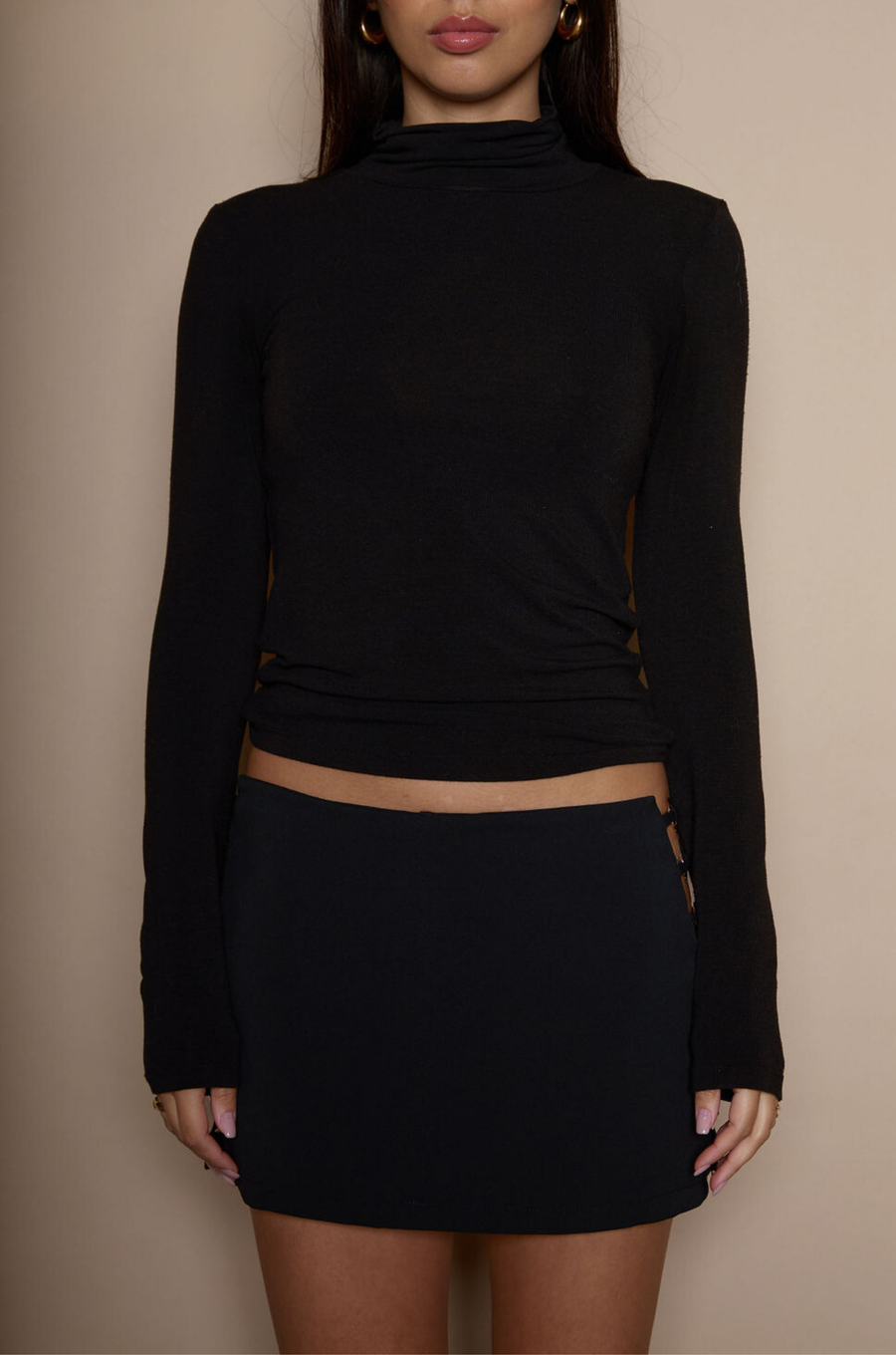 Knit skirt. Open sides with gold metal ring details. Shorts lining. Back hook and eye and zipper closures. black mini skirt