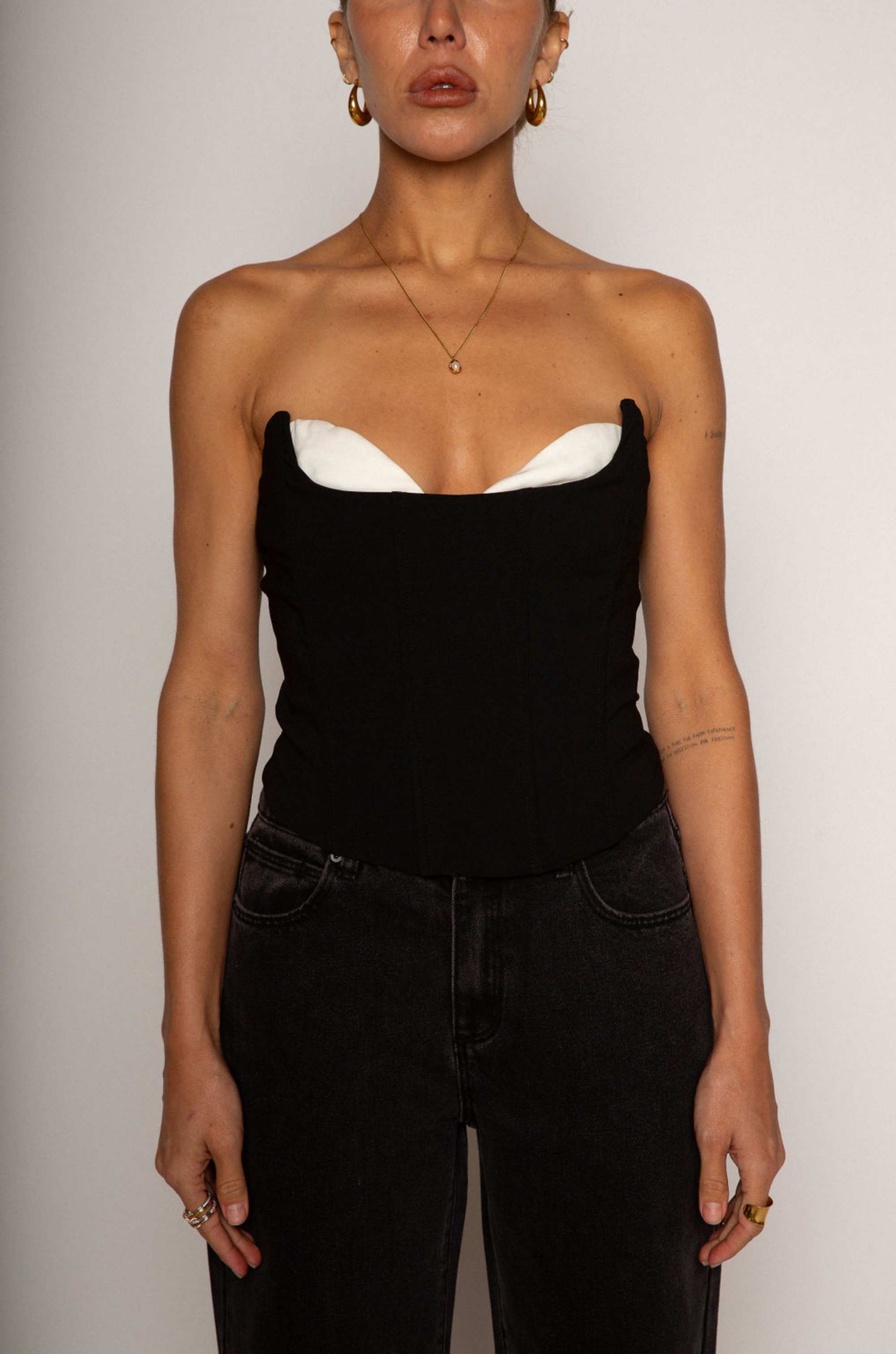 Color blocked woven bustier. Strapless neckline with inner rubber grip lining. Boning in bodice. Back hook and eye and zipper closures. Fully lined. black corset. going out top