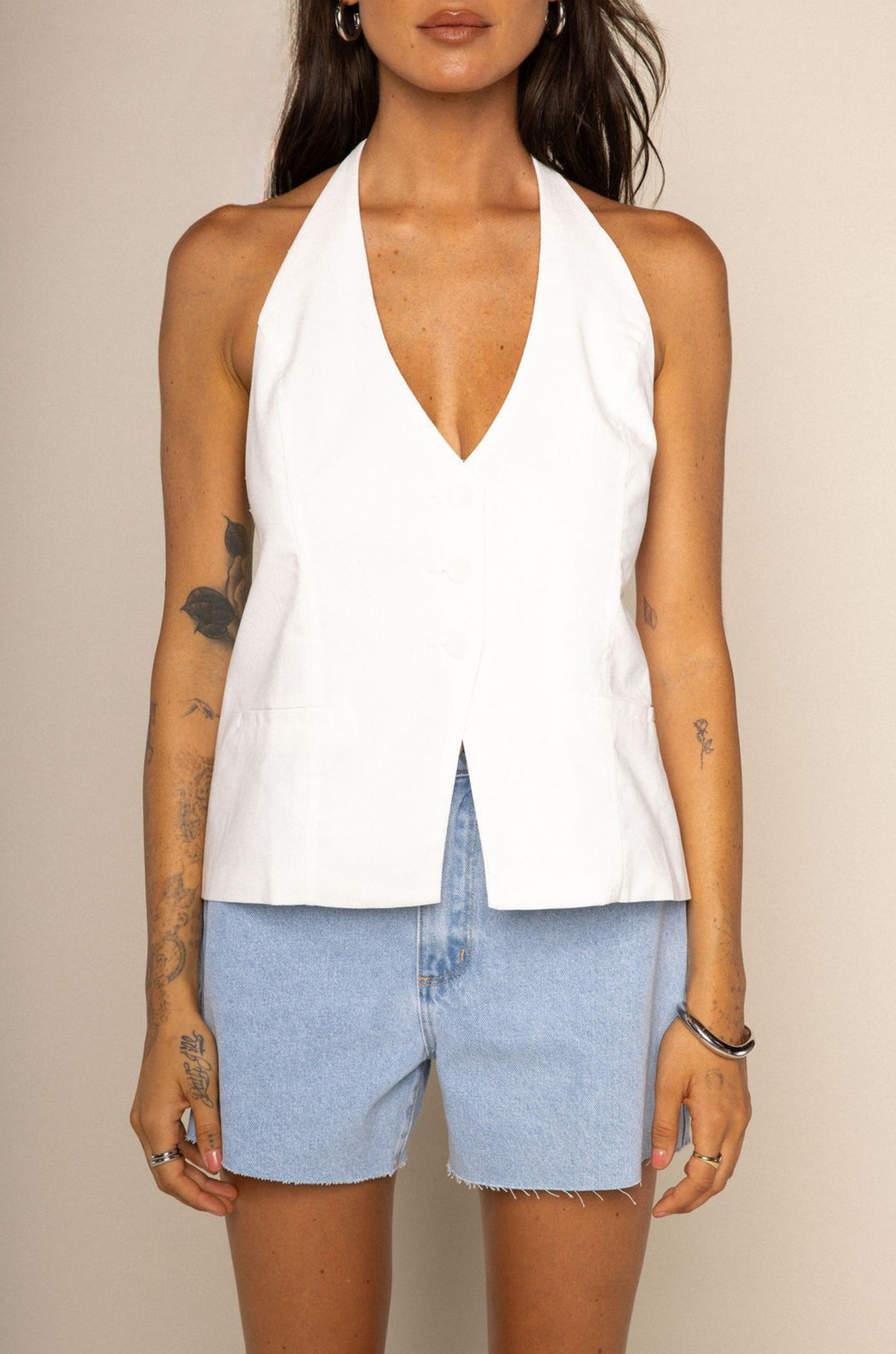 white Halter vest relaxed top
Adjustable neck and back tie
Button down closure
Faux front pockets
Lined