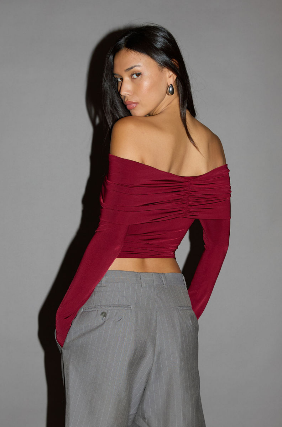 Knit crop top. Strapless elastic folded neckline. Front and back ruching. Long sleeves. Unlined. red off the shoulder long sleeve top. burgundy off the shoulder long sleeve top. holiday outfit. holiday look. christmas top. christmas outfit