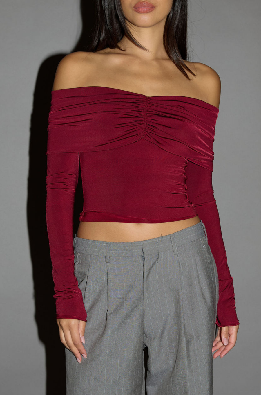 Knit crop top. Strapless elastic folded neckline. Front and back ruching. Long sleeves. Unlined. red off the shoulder long sleeve top. burgundy off the shoulder long sleeve top. holiday outfit. holiday look. christmas top. christmas outfit