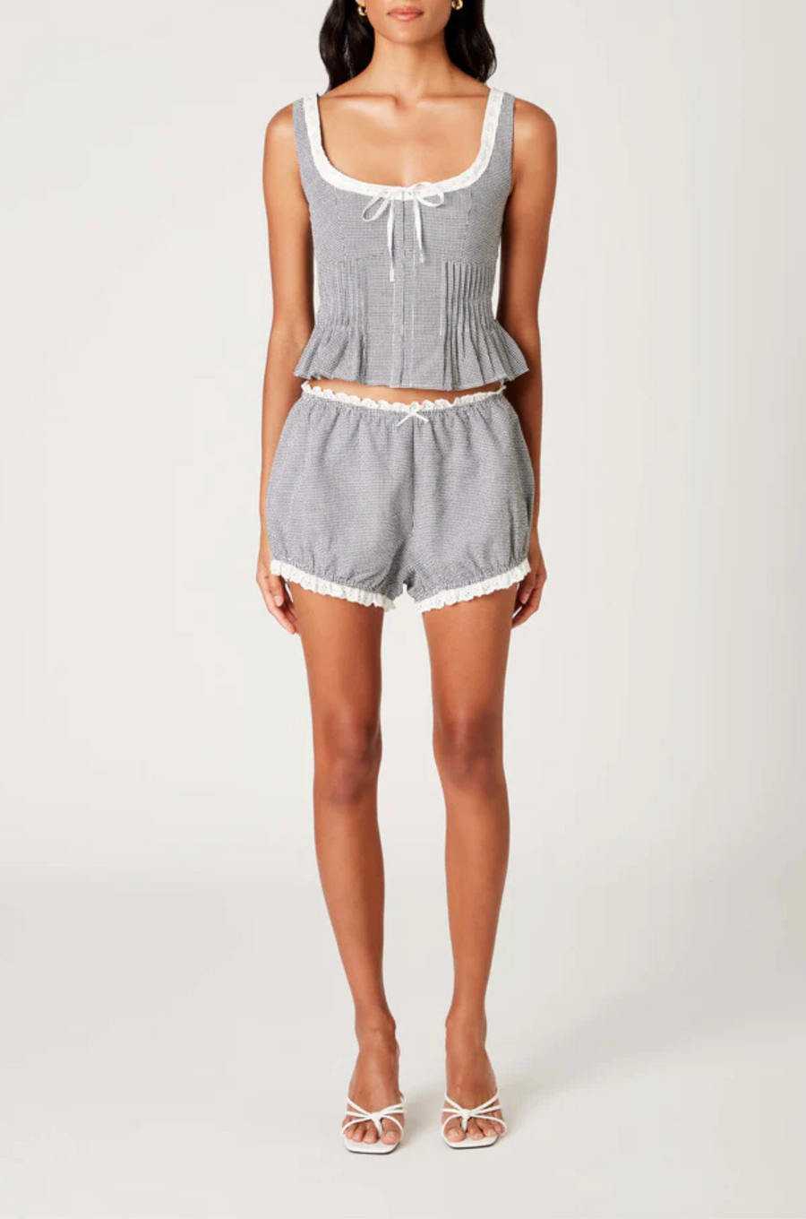 Gingham printed tank top
Figure-hugging bodice with peplum hem
Bodice pleating
Scoop neck with delicate trim bow detailing
Front hook eyelet closure
black and white gingham tank top