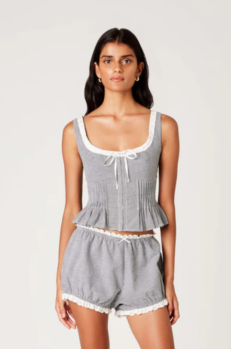 Gingham printed tank top
Figure-hugging bodice with peplum hem
Bodice pleating
Scoop neck with delicate trim bow detailing
Front hook eyelet closure
black and white gingham tank top