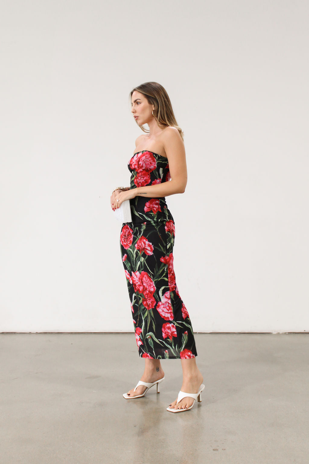 Floral printed knit mesh dress. Elastic strapless neckline. Inner rubber grip lining. Back slit. Black dress with large red floral. 