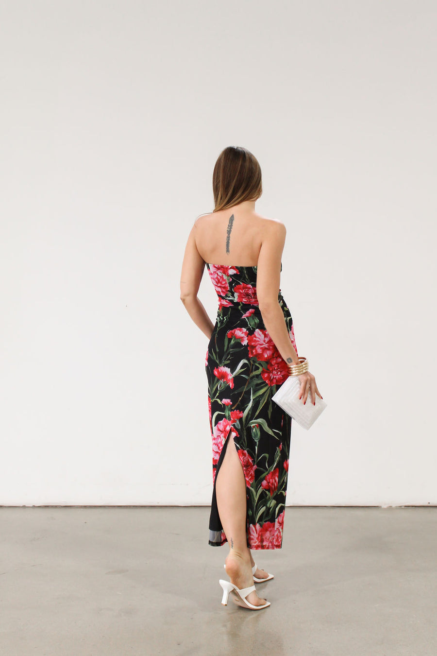 Floral printed knit mesh dress. Elastic strapless neckline. Inner rubber grip lining. Back slit. Black dress with large red floral. 