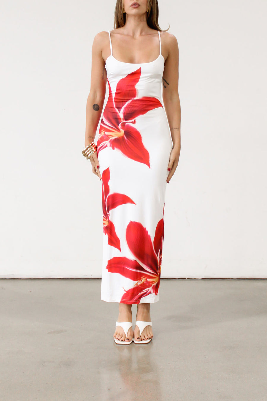 Floral printed knit maxi dress. Adjustable straps. Back slit. Fully lined. White maxi dress with crimson lily print.