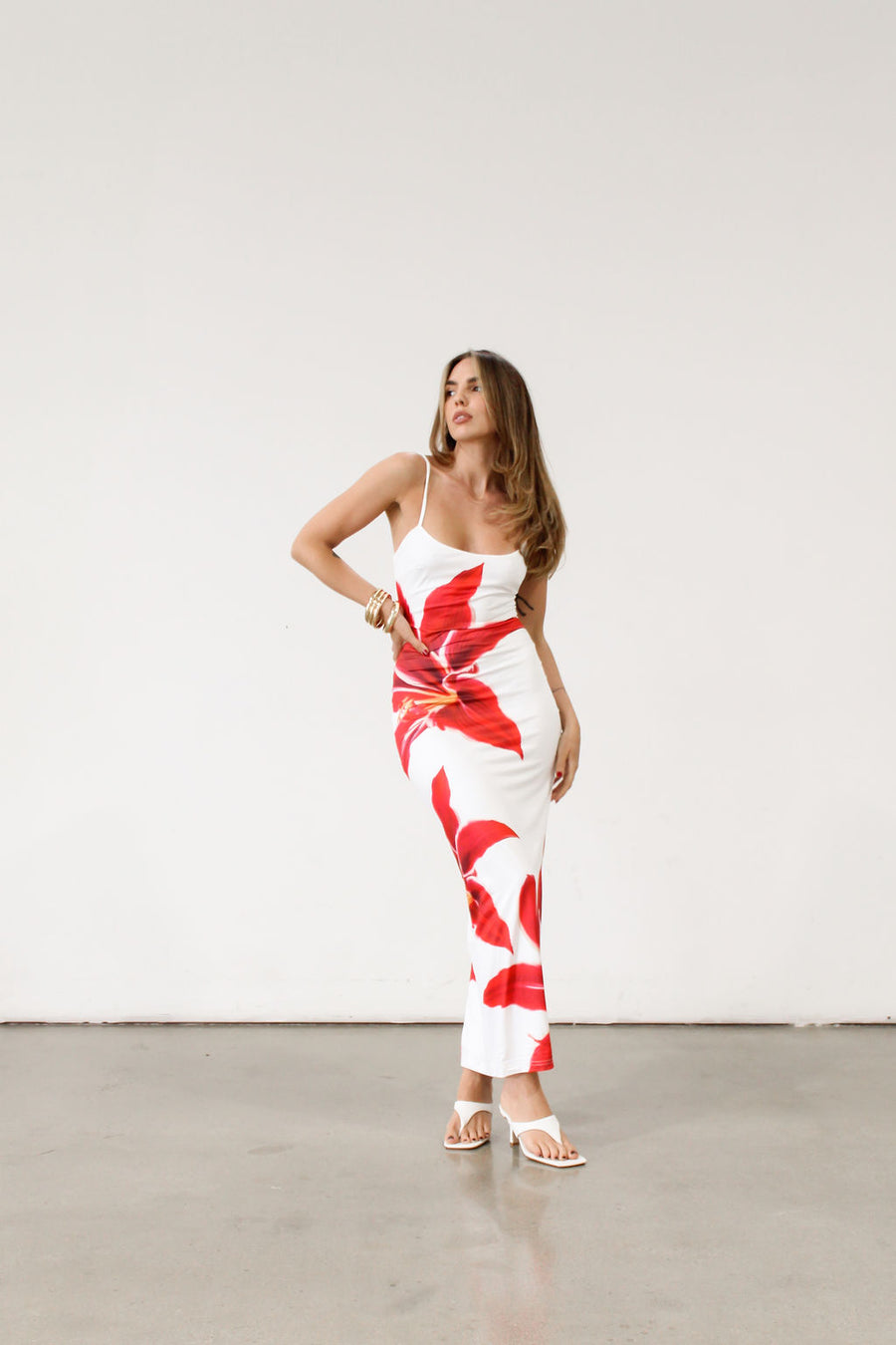 Floral printed knit maxi dress. Adjustable straps. Back slit. Fully lined. White maxi dress with crimson lily print.