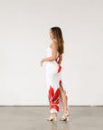 Floral printed knit maxi dress. Adjustable straps. Back slit. Fully lined. White maxi dress with crimson lily print.