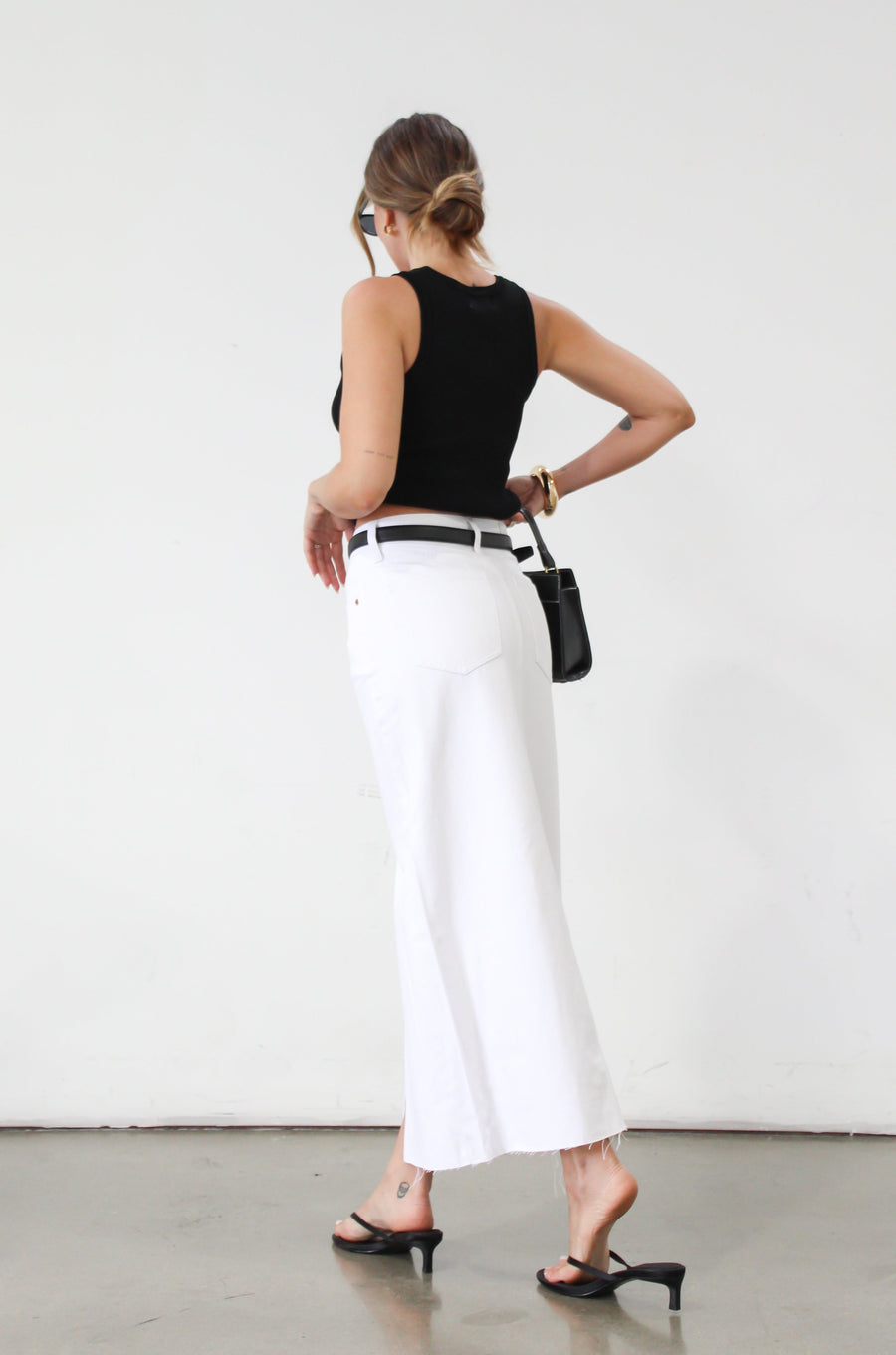 Denim midi skirt. Button and zipper fly. Five pocket construction. Front slit. Raw hem. Unlined. Relaxed fit that's designed to sit at the hips. No stretch. white denim maxi skirt. denim skirt with slit. 