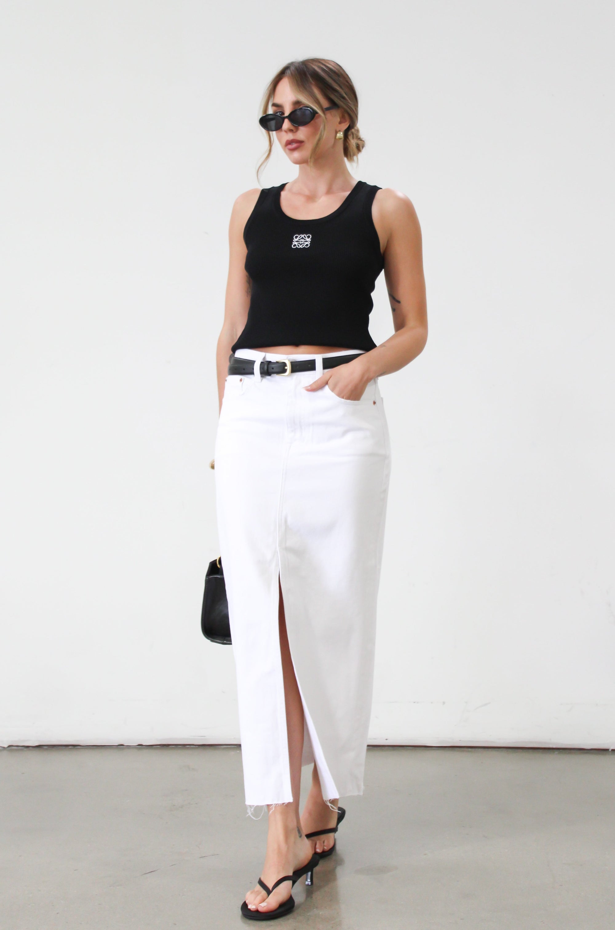 Denim midi skirt. Button and zipper fly. Five pocket construction. Front slit. Raw hem. Unlined. Relaxed fit that's designed to sit at the hips. No stretch. white denim maxi skirt. denim skirt with slit. 
