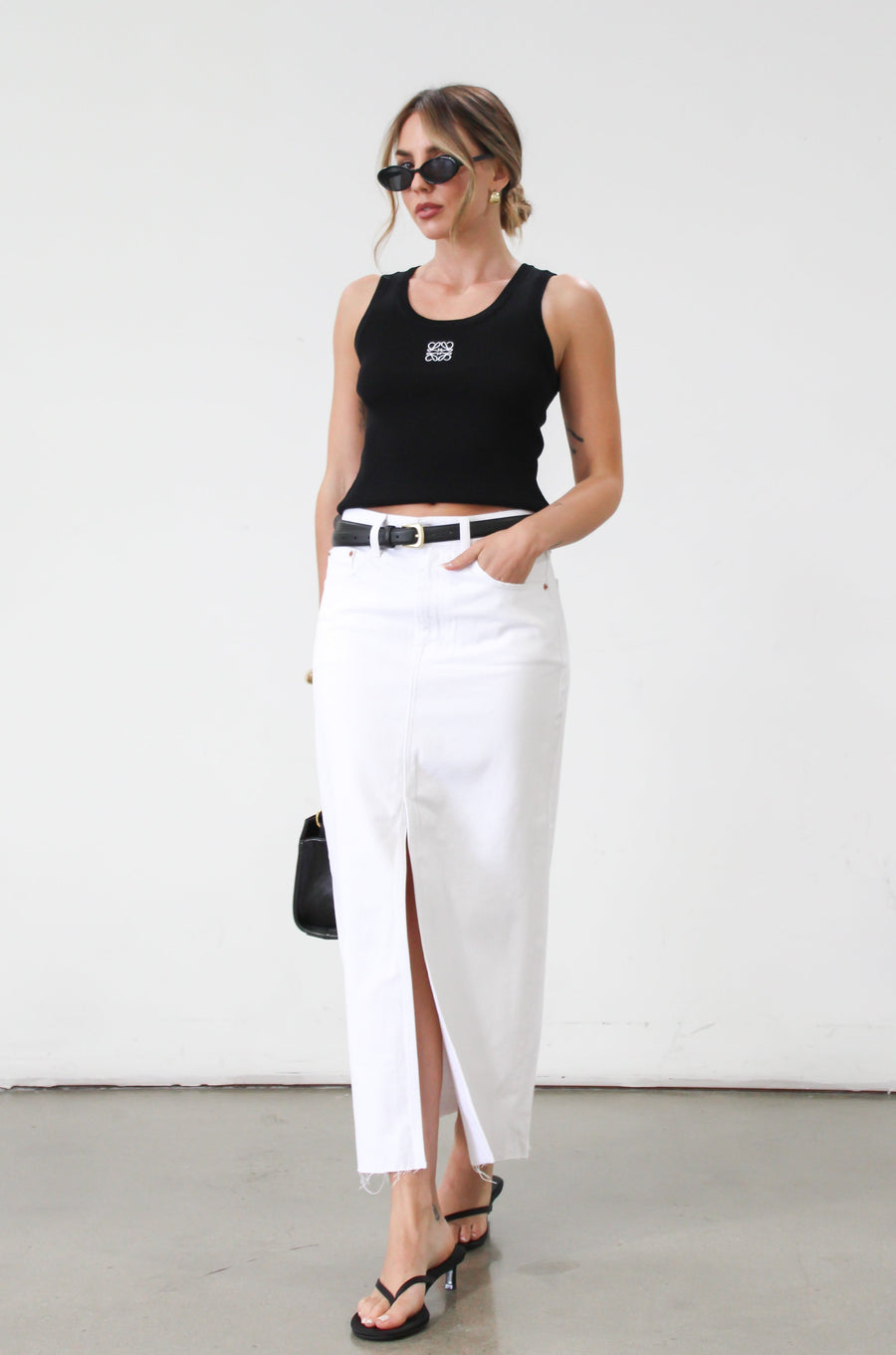 Denim midi skirt. Button and zipper fly. Five pocket construction. Front slit. Raw hem. Unlined. Relaxed fit that's designed to sit at the hips. No stretch. white denim maxi skirt. denim skirt with slit. 